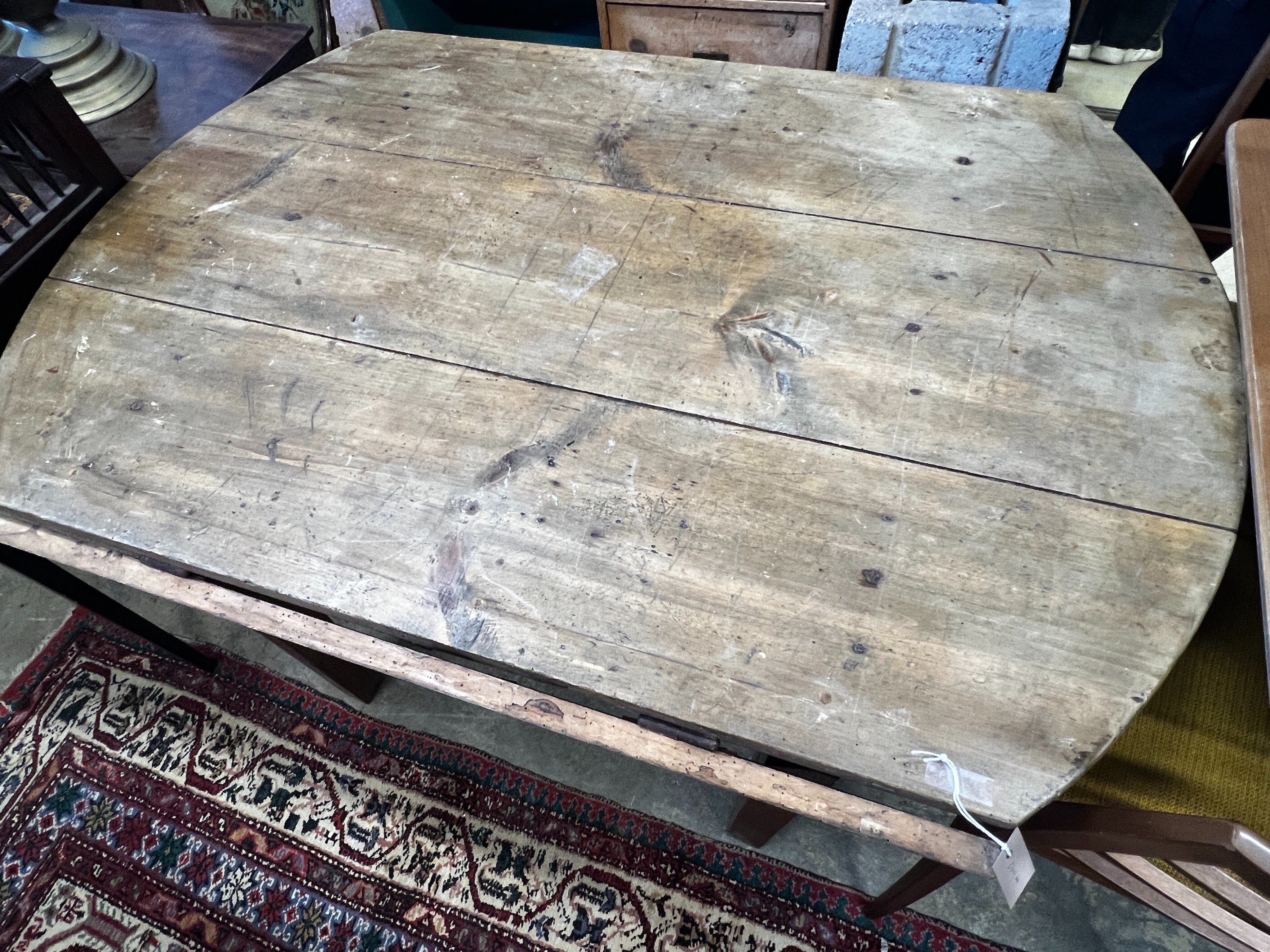 A 19th century French oak and pine circular drop leaf kitchen table, length 130cm, depth 90cm, height 73cm